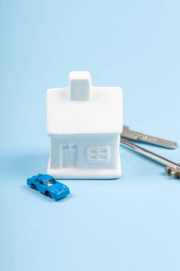 Oyuncak ev ve araba, anahtarlar mavi arka planda. Emlak satın alımı krediyle