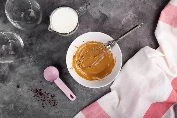 Cooking a popular Korean Dalgon coffee step by step. Step 5 soluble coffee, sugar and hot water whipped into lush foam on dark grey background. Flat Lay, top view