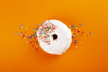 Beyaz kremalı çörek ve turuncu arka planda çok renkli tatlı. Üst görünüm