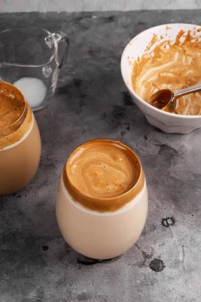 Popular drink Korean dargon coffee made of instant coffee, sugar, hot water and milk in glass on grey background