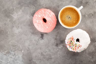 Beyaz kahve ve beyaz ve pembe kremalı donut ve gri arka planda çok renkli şekerli pasta. Üst Manzara. Boşluğu kopyala