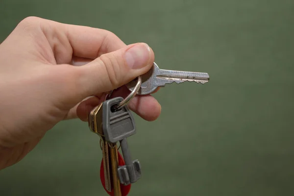 绿色背景的男人手里拿着门锁的老式钥匙 — 图库照片