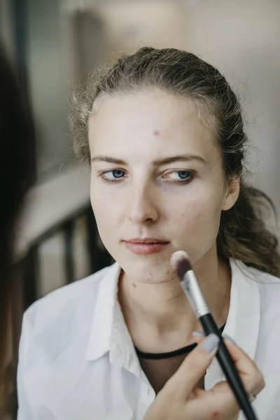 Portrait of a young girl doing make-up in a beauty salon. Series makeup before and after