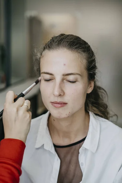 Portrait of a young girl doing make-up in a beauty salon. Series makeup before and after