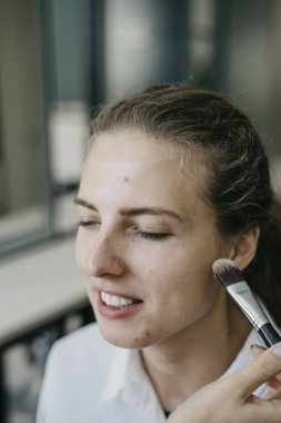 Genç kız bir salonda makyaj yapıyor