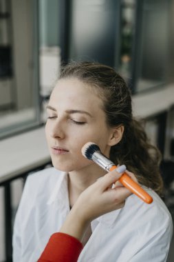 Genç kız bir salonda makyaj yapıyor