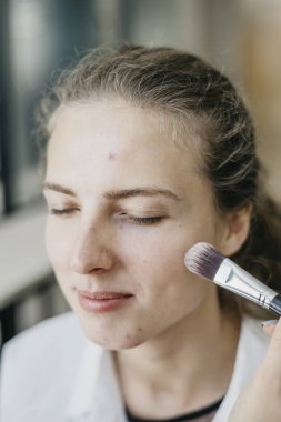 Genç kız bir salonda makyaj yapıyor