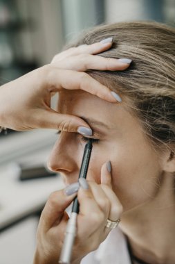 Genç kız bir salonda makyaj yapıyor