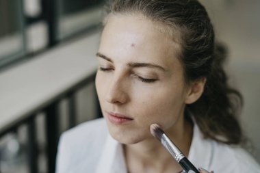 Genç kız bir salonda makyaj yapıyor