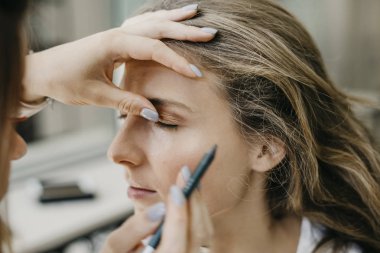 Genç kız bir salonda makyaj yapıyor