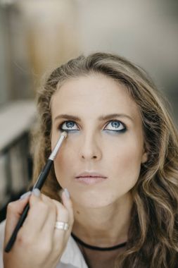 Genç kız bir salonda makyaj yapıyor