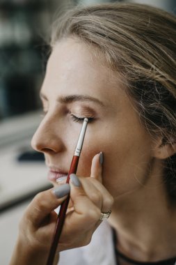 Genç kız bir salonda makyaj yapıyor