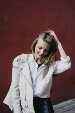 Kadın kırmızı duvarının yakınında beyaz ceketli