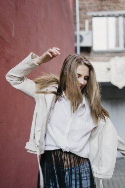 Kadın kırmızı duvarının yakınında beyaz ceketli