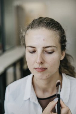 Genç kız bir salonda makyaj yapıyor