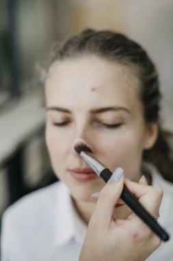 Genç kız bir salonda makyaj yapıyor