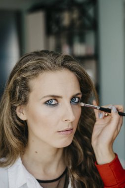 Genç kız bir salonda makyaj yapıyor