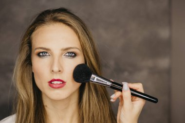 güzel bir genç kadın makyaj uygulamak 