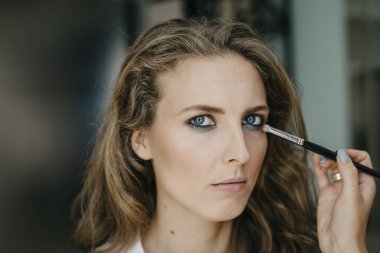 Genç kız bir salonda makyaj yapıyor