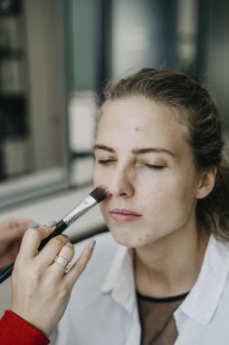 Genç kız bir salonda makyaj yapıyor