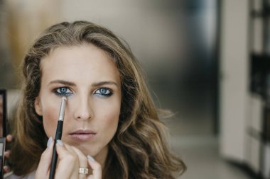 Genç kız bir salonda makyaj yapıyor