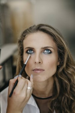 Genç kız bir salonda makyaj yapıyor