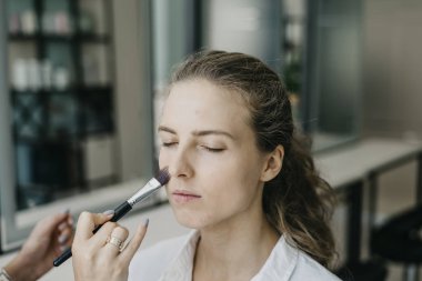 Genç kız bir salonda makyaj yapıyor