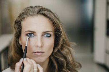 Genç kız bir salonda makyaj yapıyor