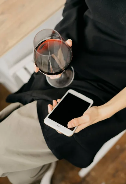 Kobieta z wina w ręku trzymając telefon — Zdjęcie stockowe
