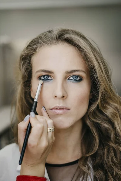 Genç kız bir salonda makyaj yapıyor