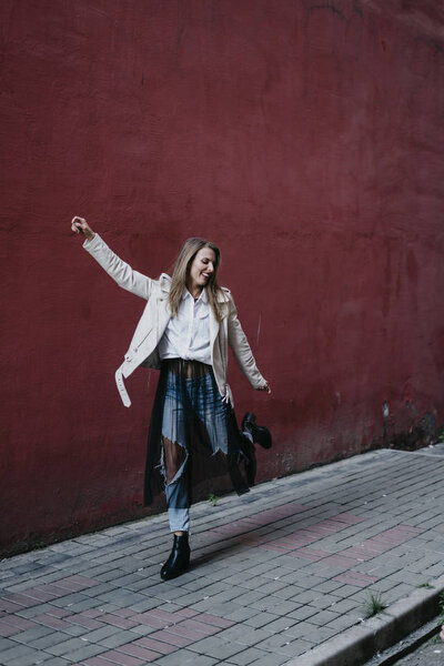 Woman in white jacket near red wall