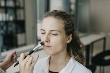 Genç kız bir salonda makyaj yapıyor