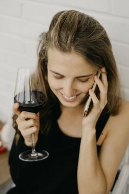 Telefon elinde tutarak şarap kadınla