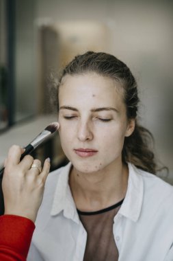 Genç kız bir salonda makyaj yapıyor