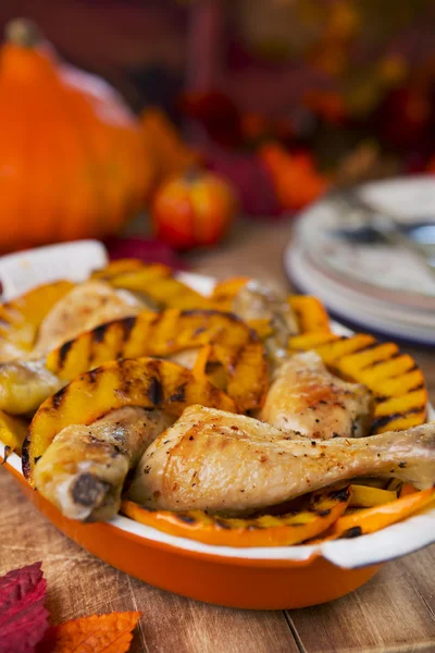 Oven roasted chicken with grilled pumpkin on a rustic table