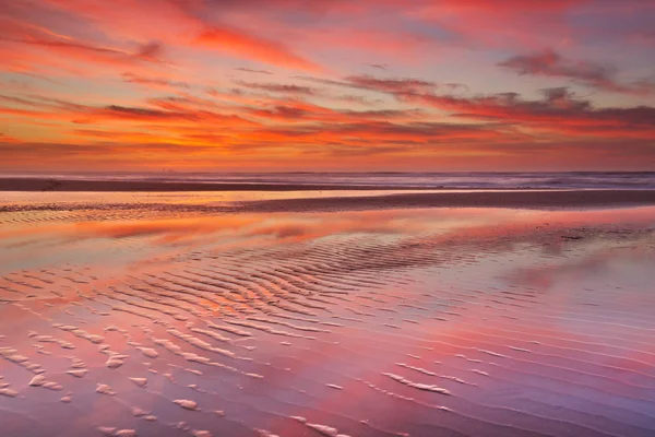 Beautiful sunset and reflections on the beach at low tide — Stock Photo, Image