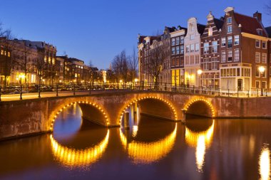 Geceleri de Amsterdam kanalları üzerinde köprüler