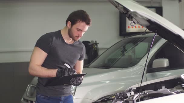 Auto Repair Nearby >> Car Mechanic Is Standing In An Auto Repair Shop Near Automobile With Open Hood And Making Notes Auto Repair Nearby >> Car Mechanic Is Standing In An Auto Repair Shop Near Automobile With Open Hood And Making Notes