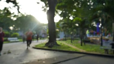 Ho Chi Minh city, Vietnam - Şubat, 2017: yavaş montin ve sun ray ile odak dışı. Kimliği belirsiz kişi çalıştıran ve güneş ışığı ile bir parkta yürüyüş