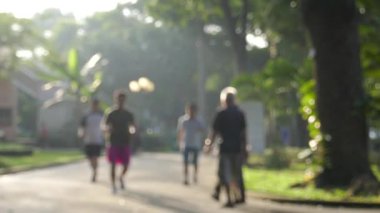 Yavaş çekim ve odak dışı. Tanımlanamayan insanlar parkta gün ışığıyla koşup yürüyorlar. Ho Chi Minh şehri, Vietnam