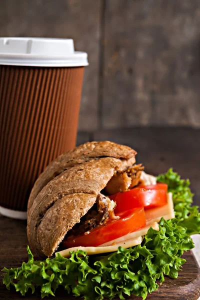 Sándwich de croissant de grano y una taza de café de cartón en una oscuridad —  Fotos de Stock