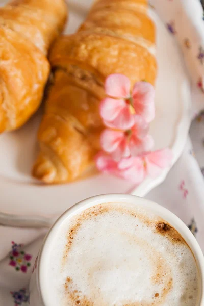 Croissants, coffee cup, flower in romantic style — Stock Photo, Image