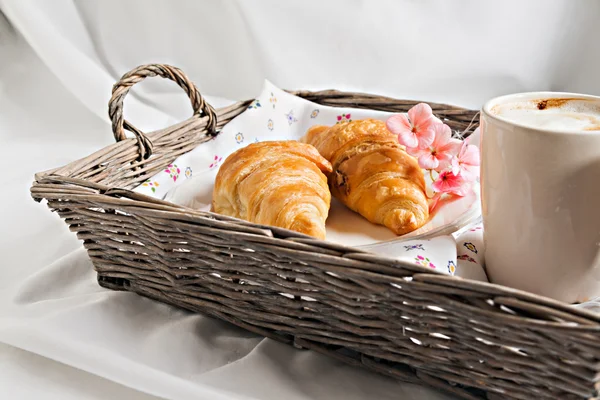 Croissants, Kaffeetasse, Blume im romantischen Stil auf einem Weidenkorb — Stockfoto