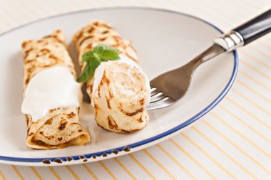 ince krepler ekşi krema nane ile pancakes tabağa haddelenmiş. 