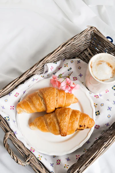 Croissants, Kaffeetasse, Blume im romantischen Stil auf einem Weidenkorb — Stockfoto