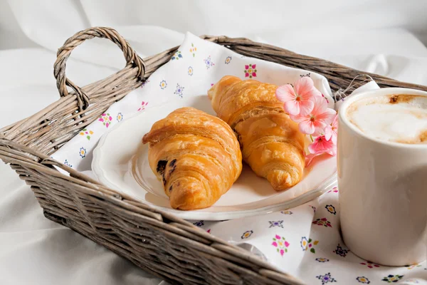 Croissanter, kaffekopp, blomst i romantisk stil på et wichker tra – stockfoto