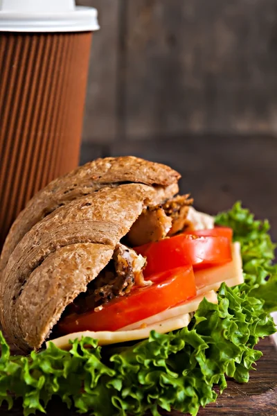 Graan croissant sandwich en een kartonnen kopje koffie op een donker — Stockfoto