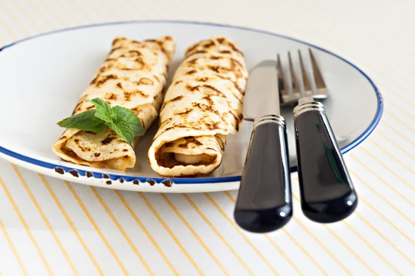 thin pancakes rolled crepes mint on a plate with knife and fork