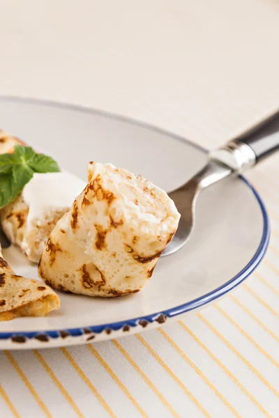 Crepes finos panqueques enrollados con crema agria menta en un plato —  Fotos de Stock