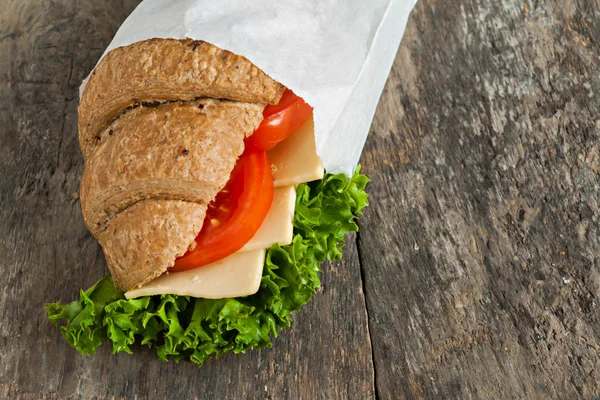 Sándwich de croissant vegetariano de grano sobre un fondo de madera viejo —  Fotos de Stock